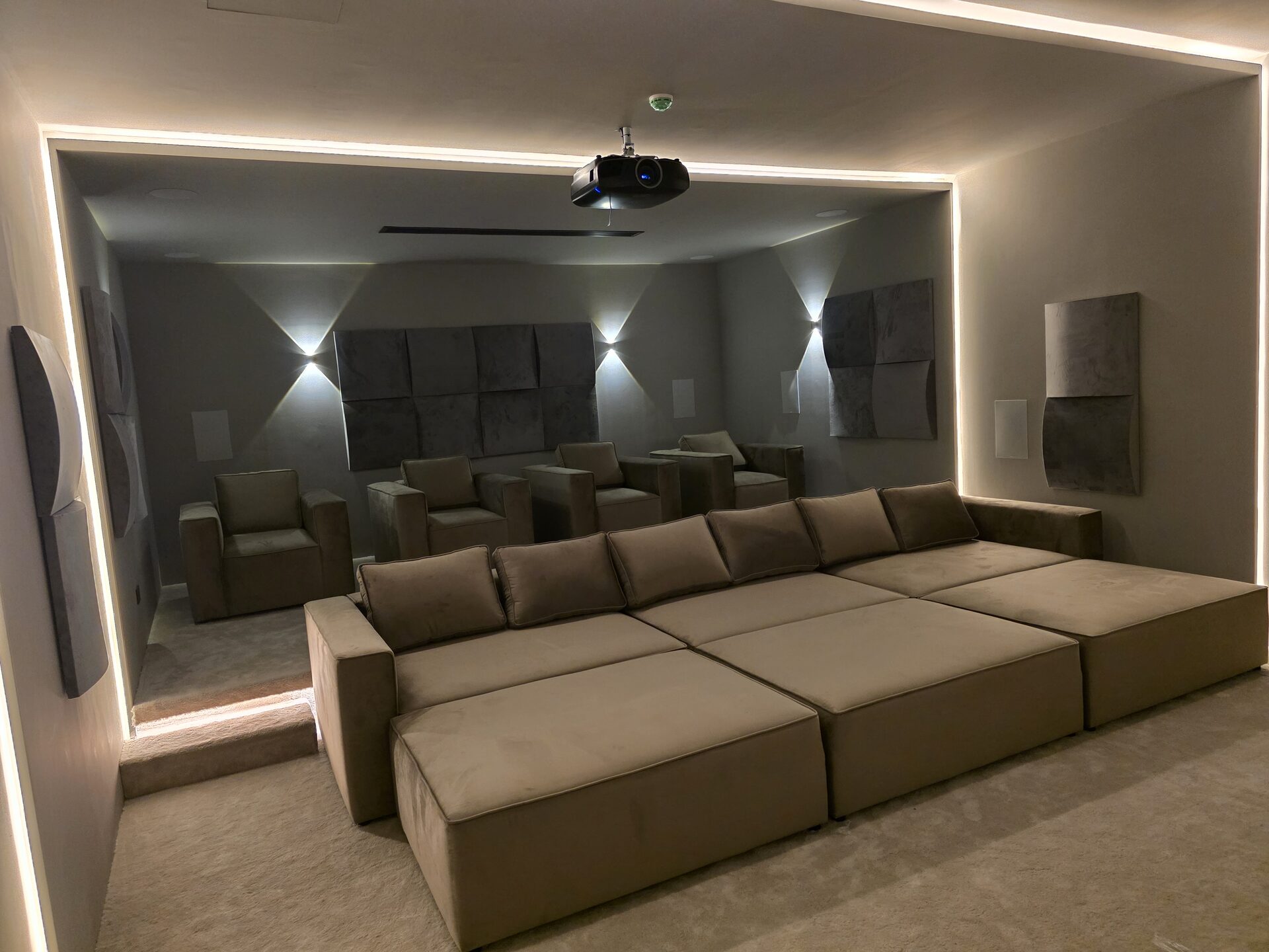 Home cinema in a Dubai Hills villa with a tiered riser, in-wall speakers and acoustic panels