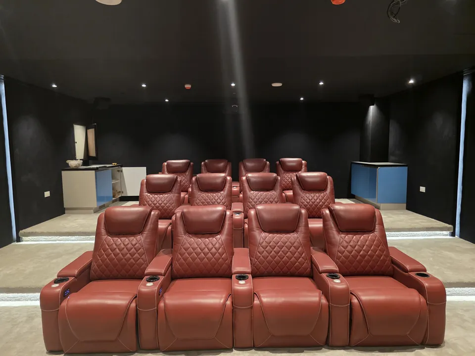 Twelve red power recliners in three rows on a stepped riser in a dark cinema room