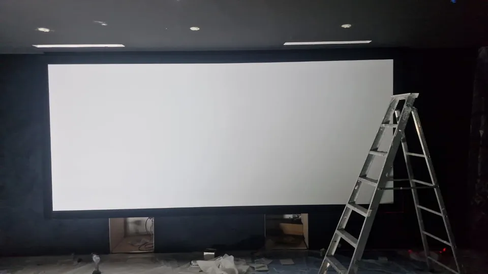 The 180-inch acoustically transparent screen being fitted