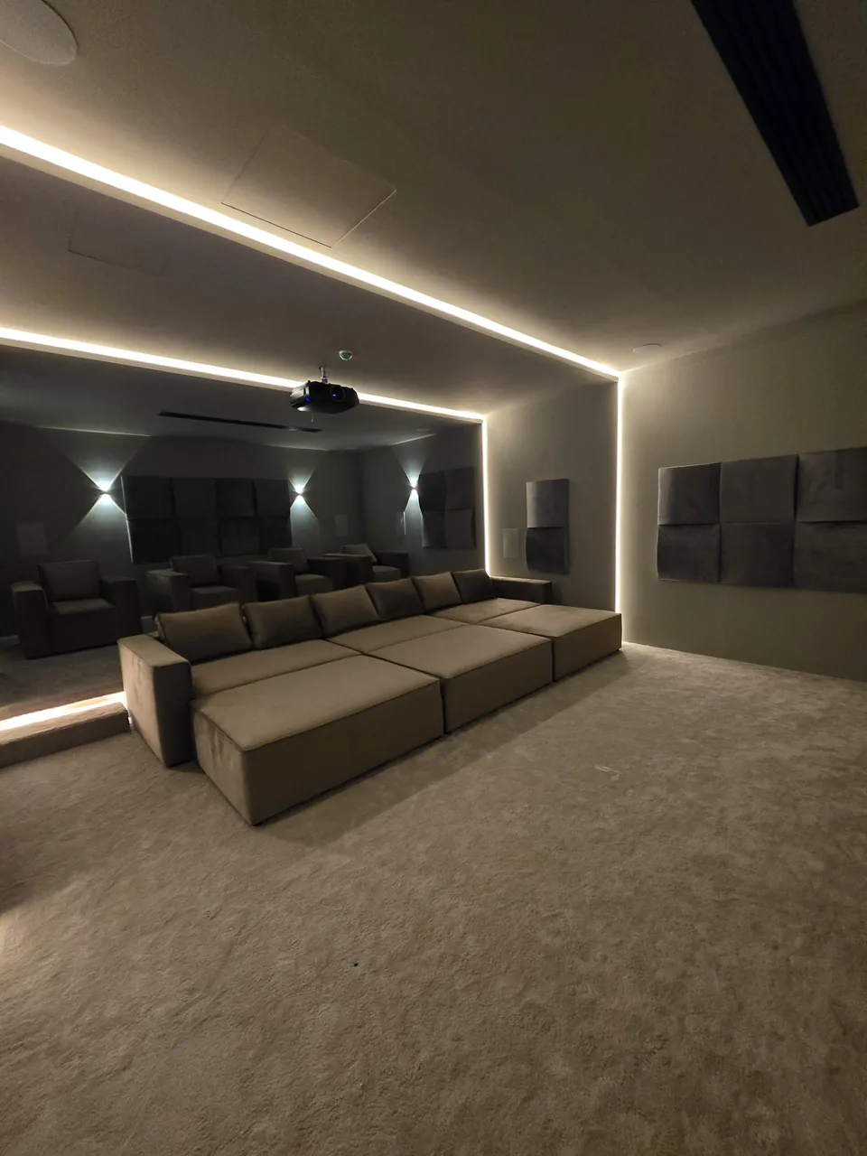 The room from the front corner, LED frame lit, rows facing the screen