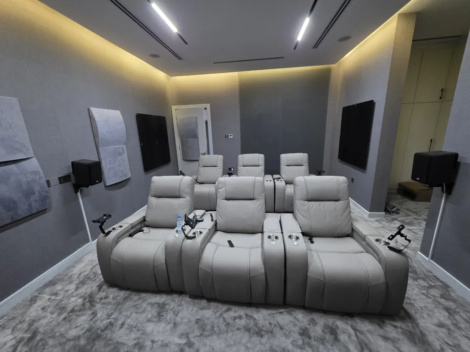 Two rows of light grey recliners in a media room with acoustic panels on the walls