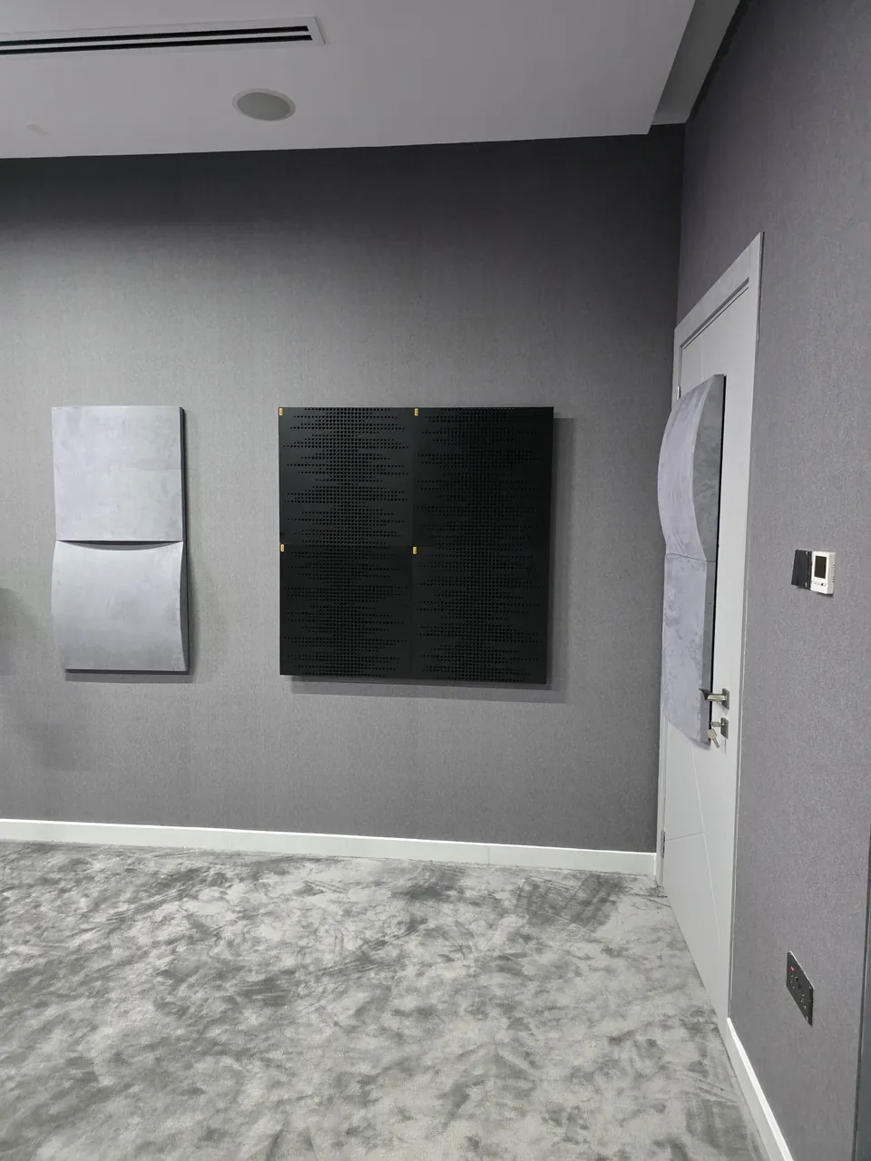 Grey absorber panels and a dark wave-wood diffuser on the side wall
